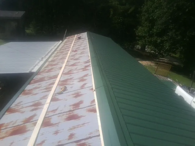 Old rusted panels beside newly installed green metal roofing — Wind Damage Roof Repair by Roofing Brothers in Oswego