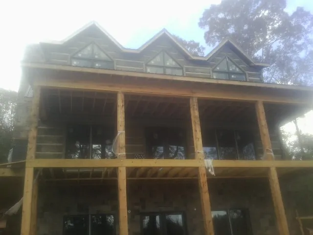 Dormers and porch framing on a large log home under construction — Roof Coating work by our crew in Oswego