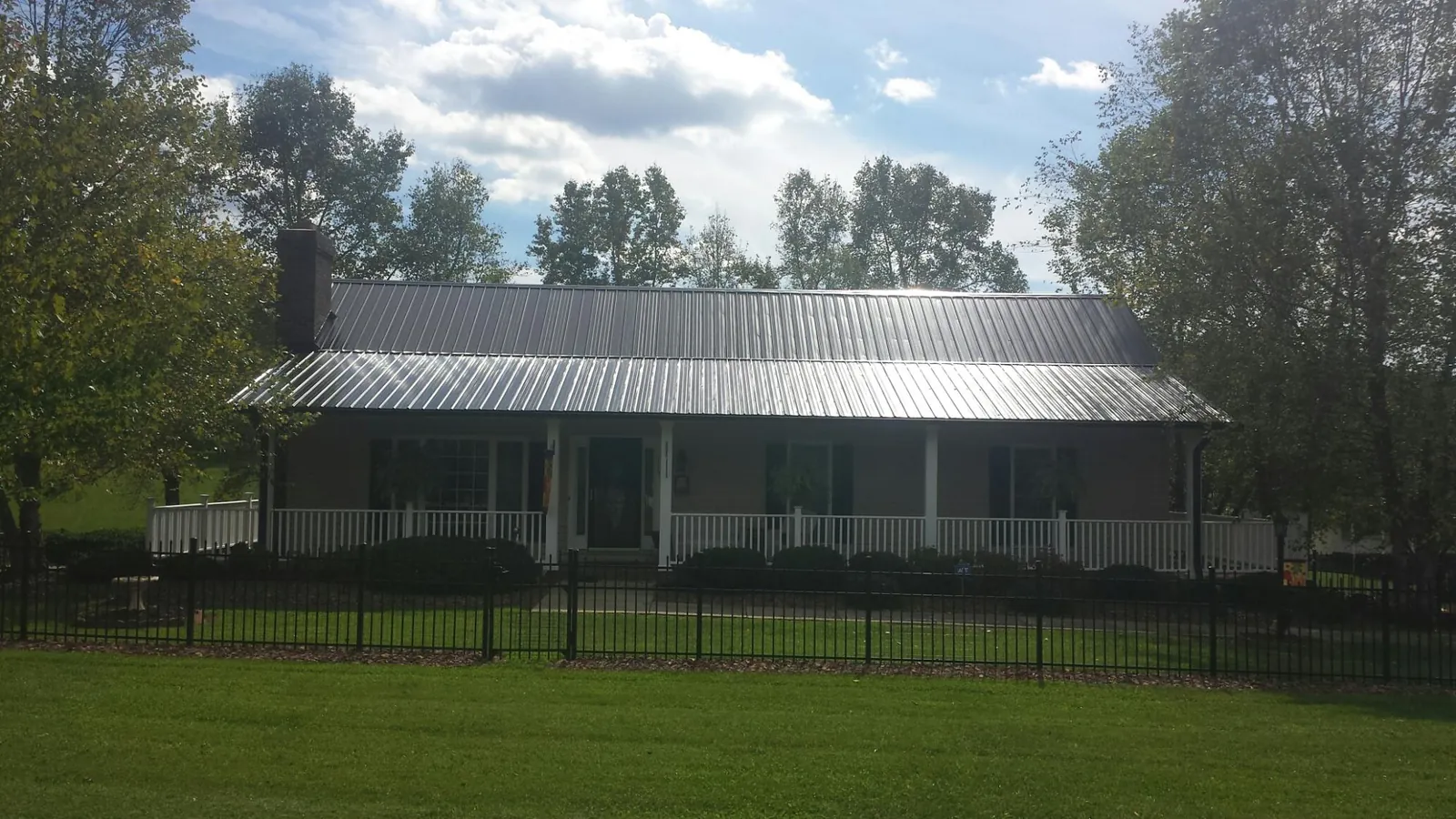 Gray metal roof on a brick ranch with a full width front porch — Gutter Guard Installation work by our crew in Oswego