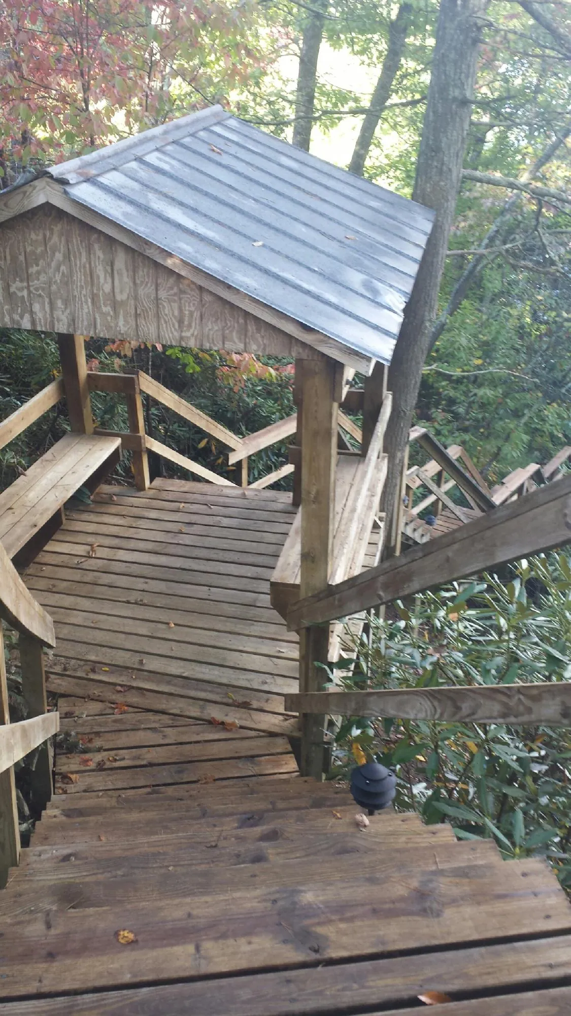 Metal roofed shelter over wooden steps on a wooded walkway — Skylight Repair & Installation work by our crew in Oswego